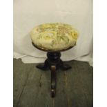 A Victorian circular piano stool on three outswept legs