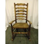 An oak rocking chair with scrolling arms and rush seat