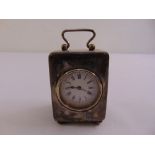 A rectangular silver mounted desk clock with white enamel dial, the case with swing handle, on