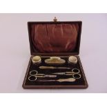 A cased silver plated manicure set to include powder bottle, a nail buffer and scissors,