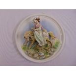 A French style circular bisque wall plaque depicting a lady riding a horse in relief