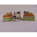 A pair of Staffordshire figurines of two sleeping figures and another German figurine of a gentleman