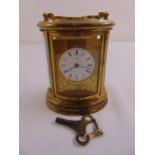 A Simmons shaped oval brass carriage clock with white dial and Roman numerals to include key