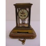 A rectangular brass and glass cased mantle clock, painted enamel dial with Arabic numerals, to