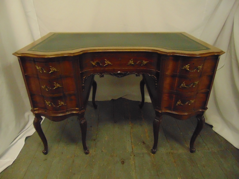 An Edwardian shaped rectangular mahogany kneehole desk with tooled leather top, brass handles, on