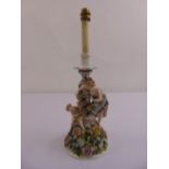 A continental porcelain table lamp figural group amidst flowers and leaves on circular base
