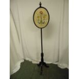 A Victorian mahogany screen pole the oval glazed panel decorated with birds and flowers
