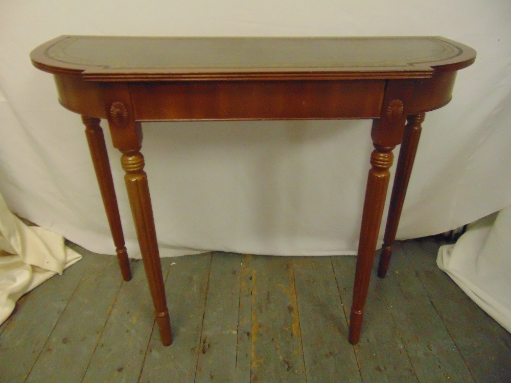 A mahogany consol table shaped oval with inlaid tooled leather top on four tapering cylindrical