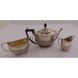 An Edwardian silver three piece teaset, oval, part fluted with angled handles, the teapot London