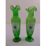 A pair of green glass vases hand painted with flowers and leaves on raised circular bases, 23.5cm (