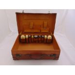 An early 20th century gentlemans leather suitcase to include five various brushes and four toilet