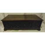 A rectangular oak blanket box with carved 17th century side panels hinged cover on four bun feet