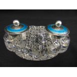 A Victorian oval cut glass ink stand with two silver and enamel inkwells, the hinged covers with