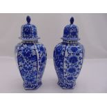 A pair of blue and white shaped hexagonal vases with pull off covers decorated with flowers and