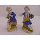 A pair of continental figurines of children in 18th century costume holding bunches of flowers, on