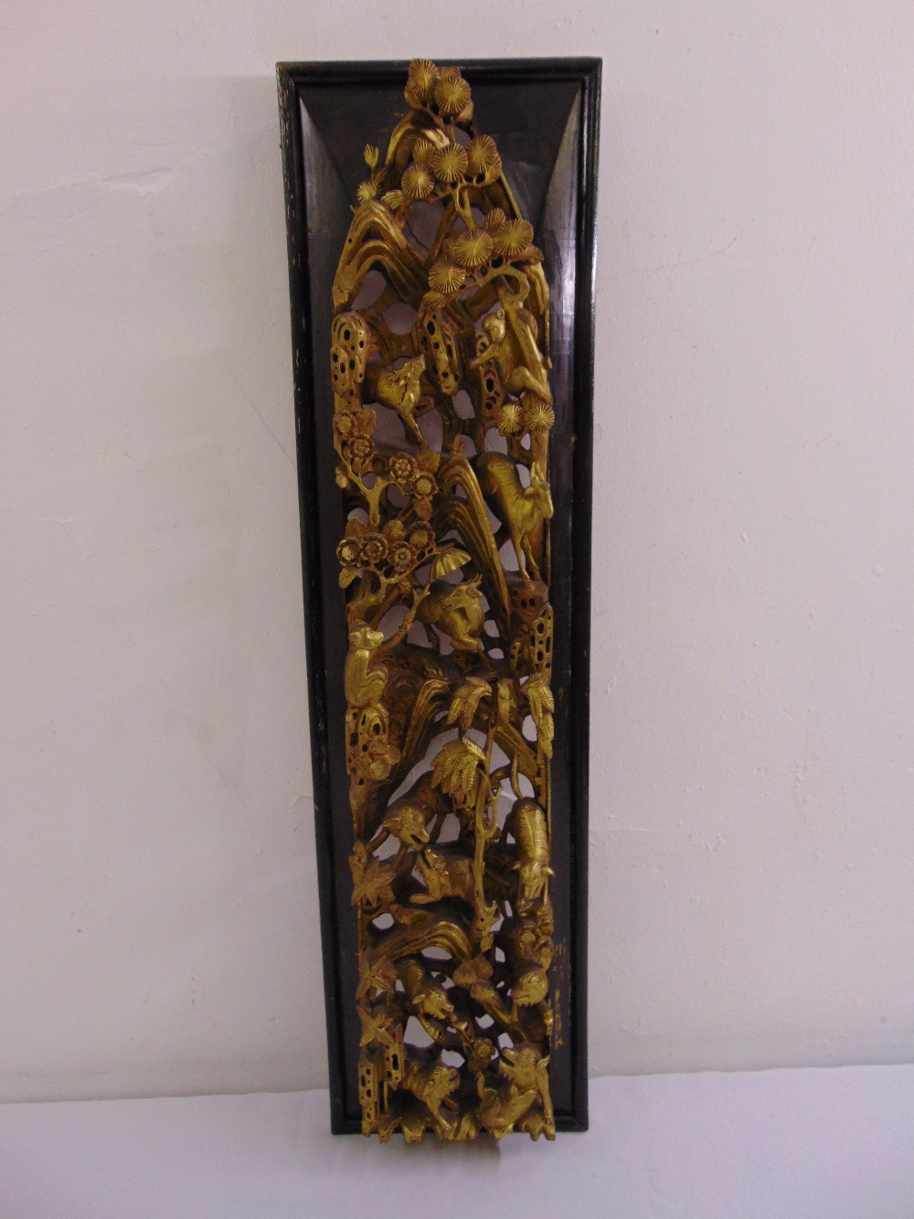 A late 19th century oriental rectangular wooden panel carved with gilded animals, trees and flowers,