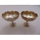 A pair of silver pedestal bowls chased with flowers and leaves on raised circular lobed feet, London