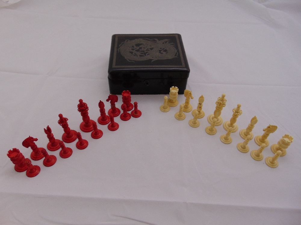 A Victorian carved bone chess set with white and red stained pieces in an accompanying lacquered