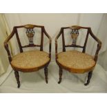 A pair of Edwardian mahogany inlaid upholstered armchairs on four turned tubular legs