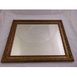A rectangular carved gilded wooden wall mirror with stylised leaf and scroll inner border, 77 x