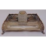 A silver rectangular desk pen and ink stand with scroll pierced gallery on four claw feet, the