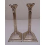 A pair of silver Corinthian column table candlesticks, on stepped square bases with gadrooned