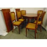 A mahogany circular dining table with two drop in leaves and six matching caned dining chairs, 78