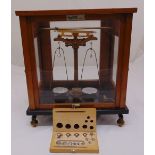 A set of brass weighing scales in glazed mahogany case with additional cased weights, 42cm (h)