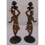A pair of cold painted bronze figurines of exotically dressed male and female supporting vase form