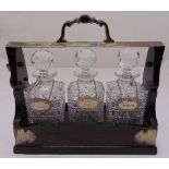 Three bottle oak framed Tantalus, the cut glass decanters with drop stoppers and wine labels