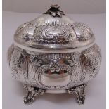 A continental white metal trinket box of lobed oval form chased with flowers and leaves, the domed