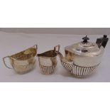 A Walker and Hall silver three piece teaset, oval, part fluted with ribbed angled handles, Sheffield