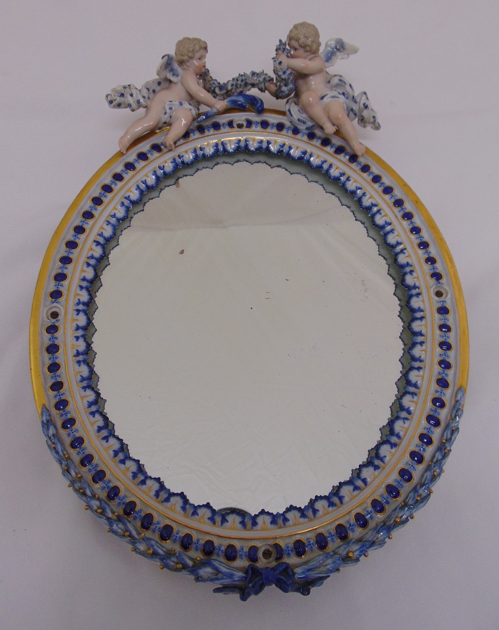 Meissen style oval boudoir mirror surmounted by two putti, A/F, 35cm (h)