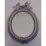 Meissen style oval boudoir mirror surmounted by two putti, A/F, 35cm (h)