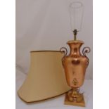 A copper table lamp in the form of a samovar with pierced scroll side handles on raised square