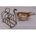 A silver cream jug, oval with cut edge, flying double scroll handle on three stepped hoof feet,