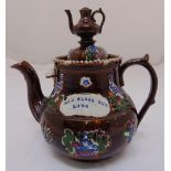 A Victorian Majolica teapot with the legend God Bless Our Home to the side, and teapot finial