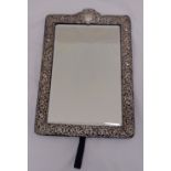 A rectangular hallmarked silver table mirror, scroll pierced border chased with flowers and