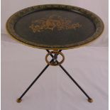 An Italian Toleware folding table, circular with gilt decoration on three tubular supports, 48.5 x