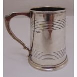 A silver mug tapering cylindrical, the sides engraved with bands with pierced scroll handle on rim