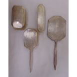 A hallmarked silver four piece dressing table set to include a hand mirror, two hair brushes and a