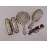 A silver dressing table set engraved with leaves and flowers comprising hand mirror, hairbrush, comb