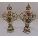 A pair of late 19th century continental bocage covered vases, flanked by putti, two pierced scroll