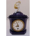 An early 20th Century KPM Berlin porcelain mantel clock with putti finial, the clock body having