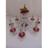 A continental white overlaid red glass chandelier with eight scrolling branches supporting candle
