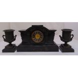 A black slate mantle clock of architectural form flanked by a pair of vase form garnitures