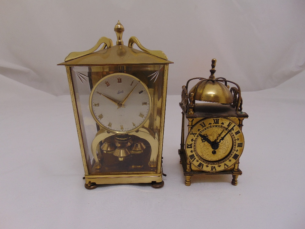 A Schatz gilt metal and glass revolving pendulum mantle clock and a miniature brass lantern clock in