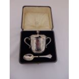 A cased silver christening set to include a porringer with scroll handles and raised pull off