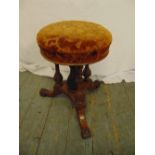 An oak piano stool with upholstered seat on triform base