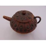 An oriental carved wooden tea pot decorated with scraffito style design and bronzed metal stud work